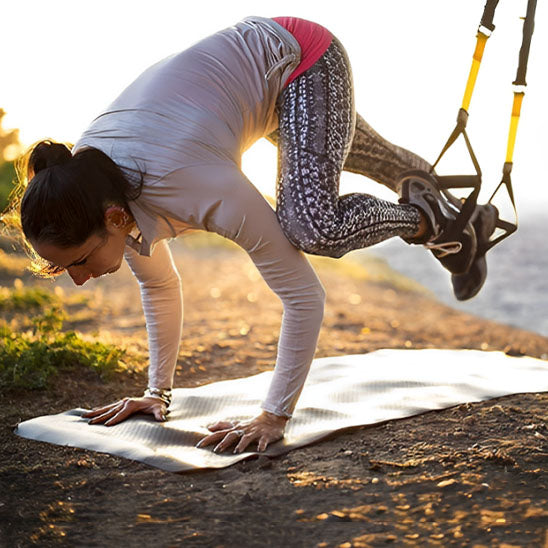 Mountain climber avec sangle musculation TRX par jeune femme plein air