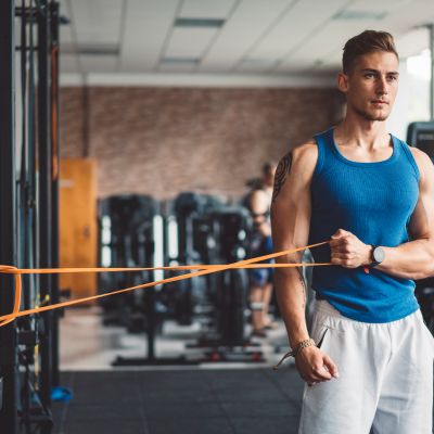 homme tirant sur elastique musculation bande resistance dans salle de sport