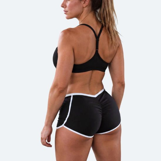 Shorts de sport femme - Dos musclé d'une femme en brassière de sport noire – short de fitness noir avec liseré blanc
