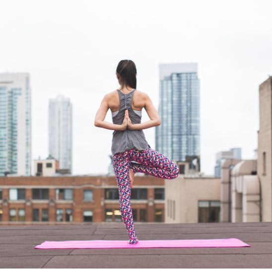 tapis pour le yoga jeune femme en equilibre sur terrasse vue urbaine